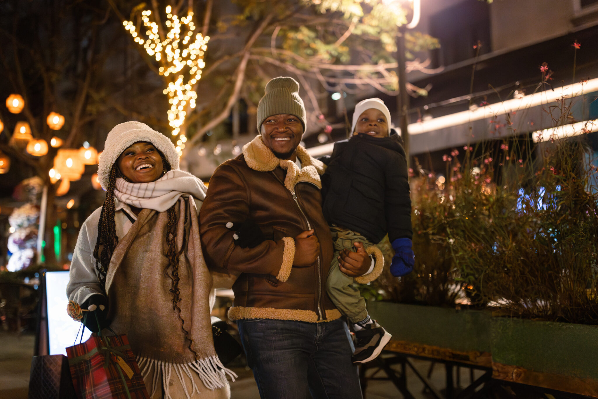 Happy family walking and enjoying a joyful evening stroll in the city during the winter season with festive lights